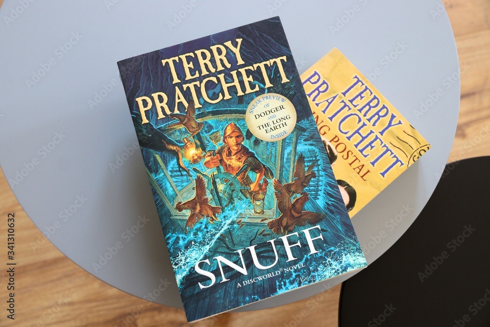 Terry Pratchett’s Snuff, a Discworld novel, displayed on a round table beside a promotional postcard.