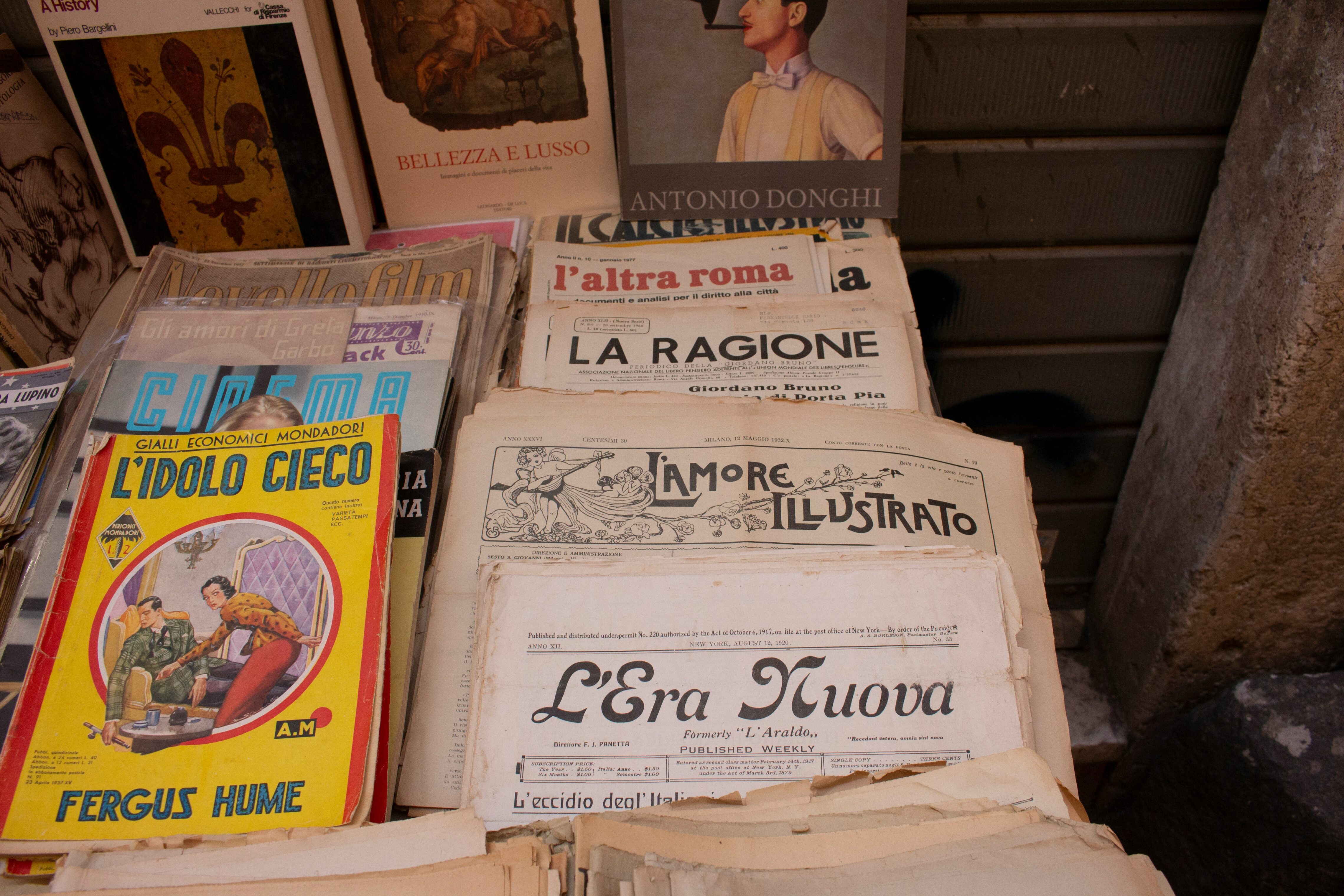 Stack of vintage Italian magazines and newspapers displayed on a table, featuring illustrated covers and bold typography.