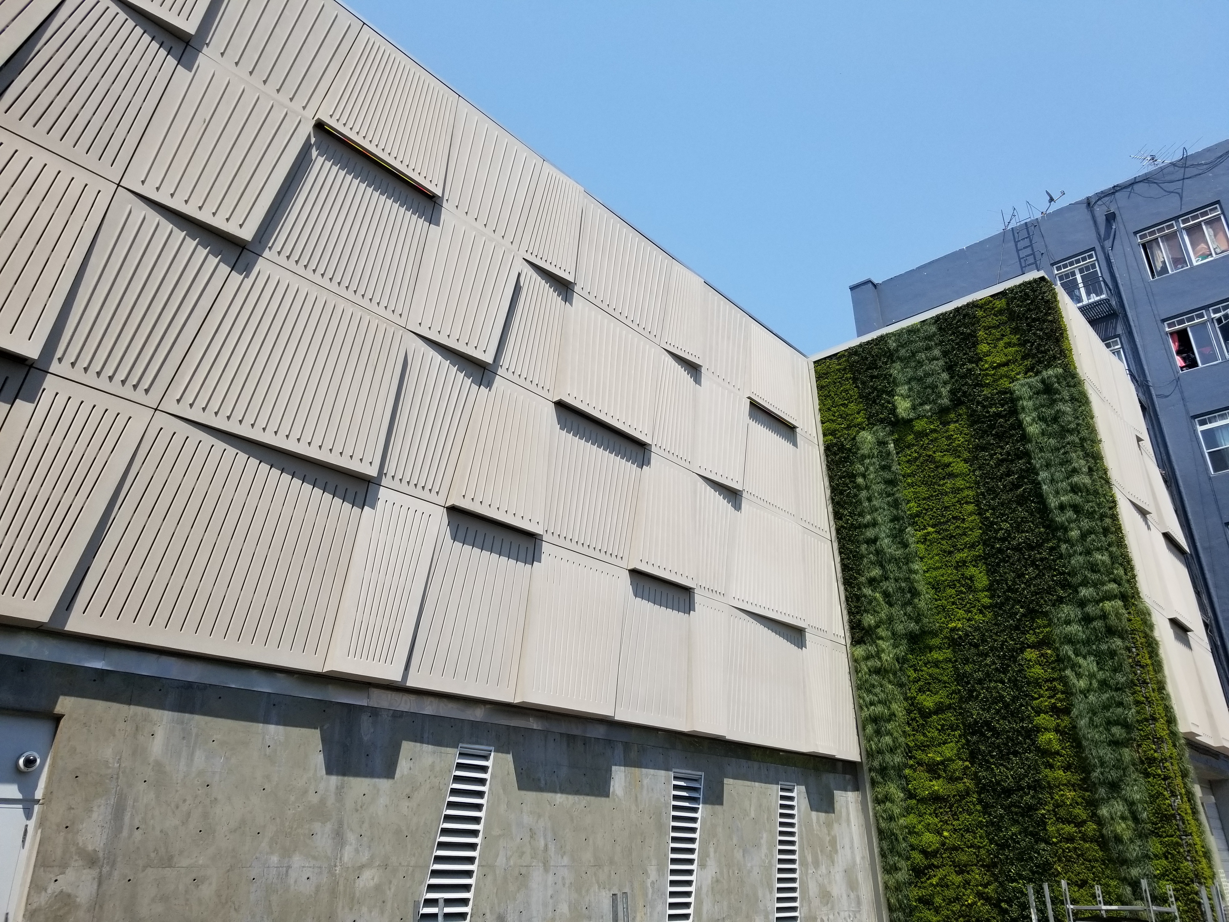 PG&E Larkin Street façade with textured concrete panels and a tall green living wall extending vertically along one side.