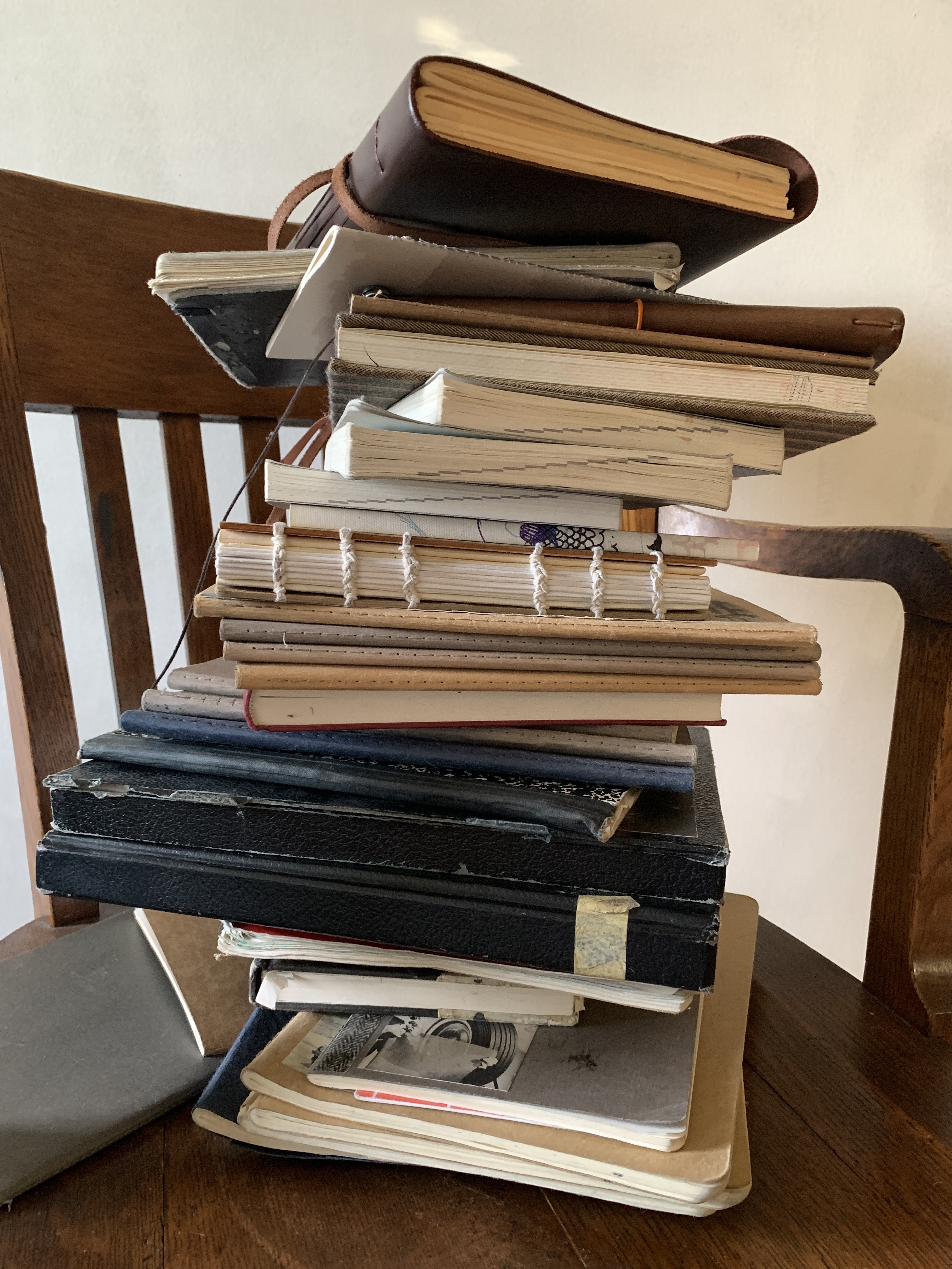 A large stack of filled journals on a chair