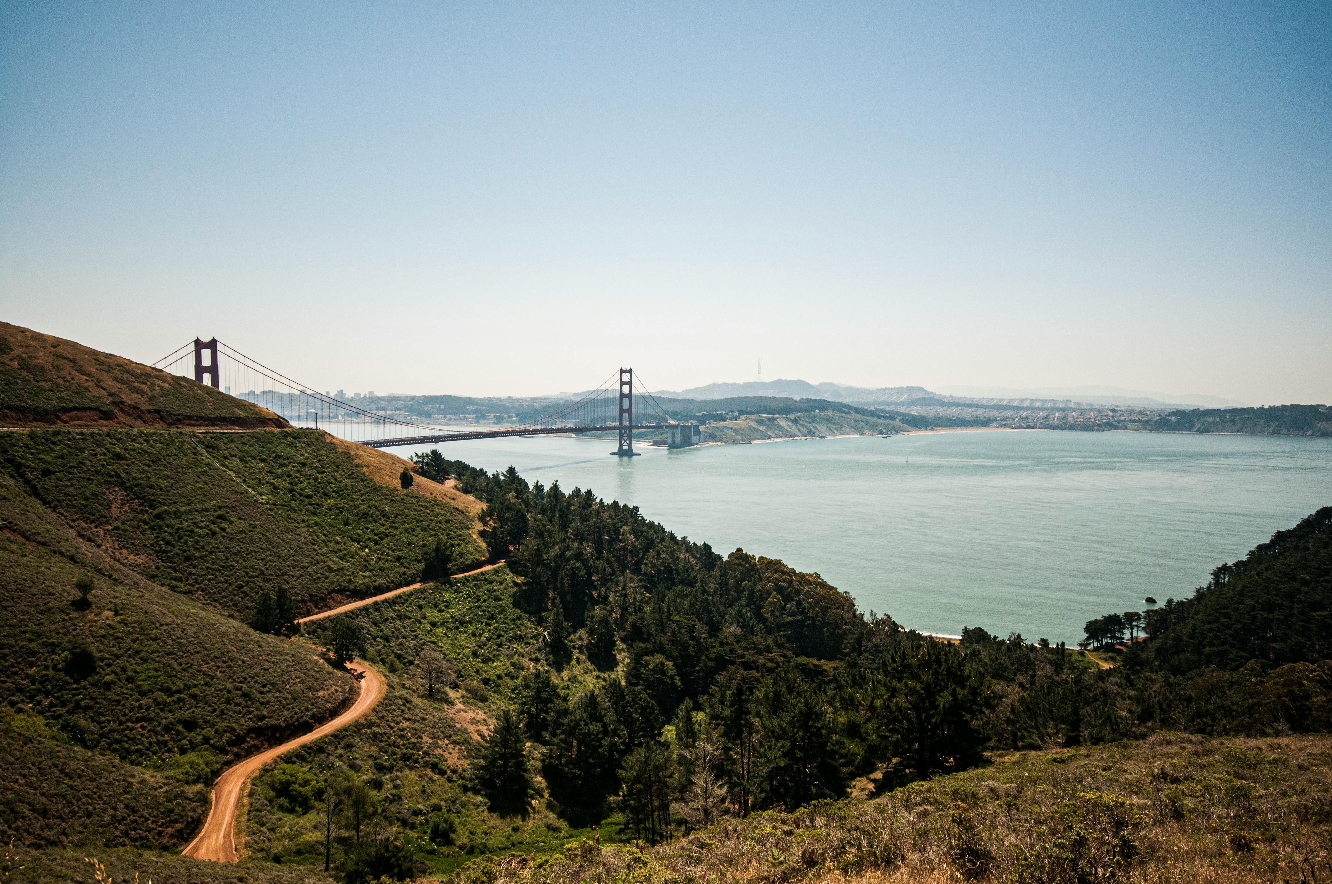 Golden Gate Bridge viewed from the Marin Headlands with hills, trees, and the bay below.