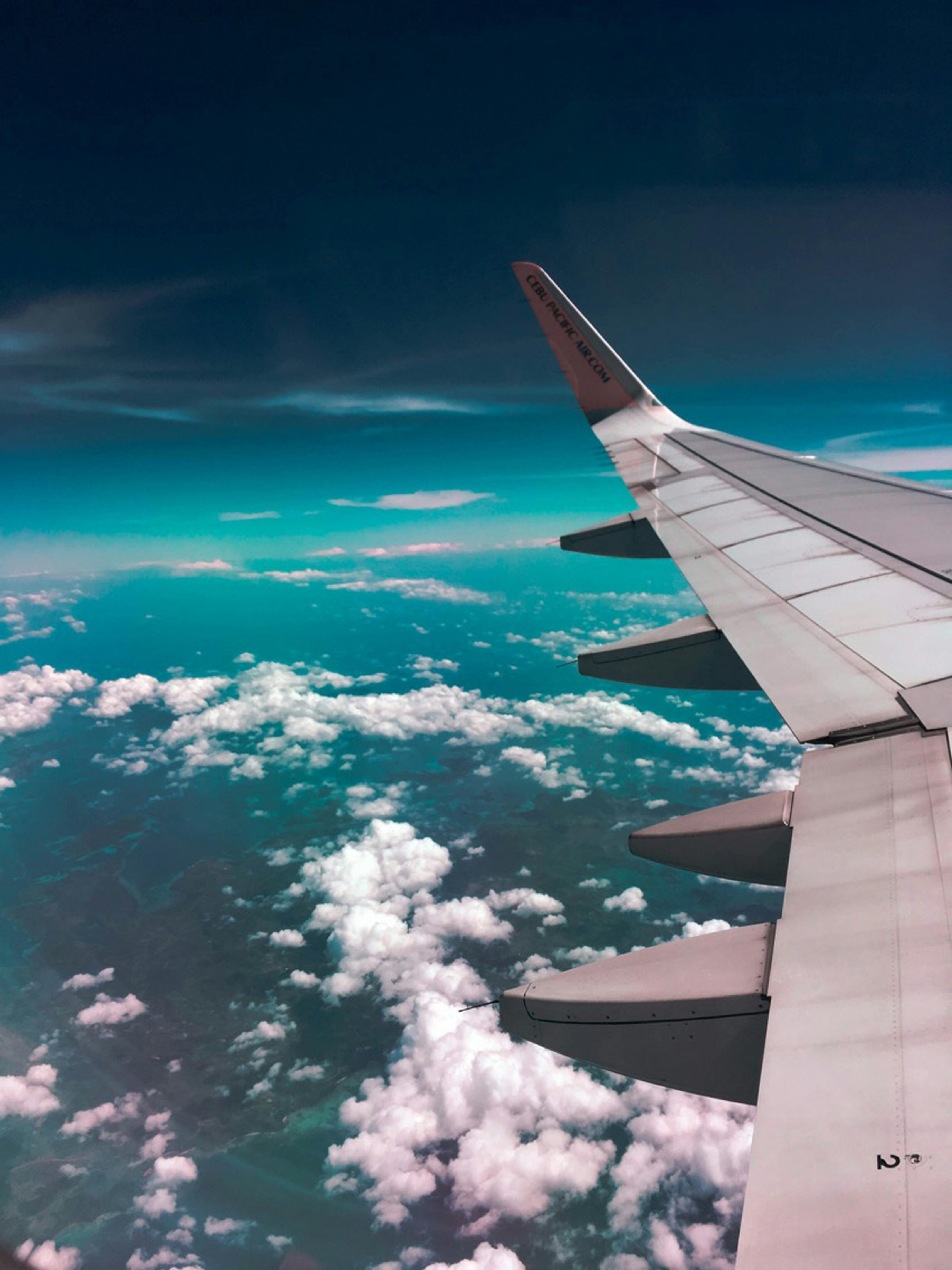 iew of airplane wing over clouds and ocean from a passenger window.