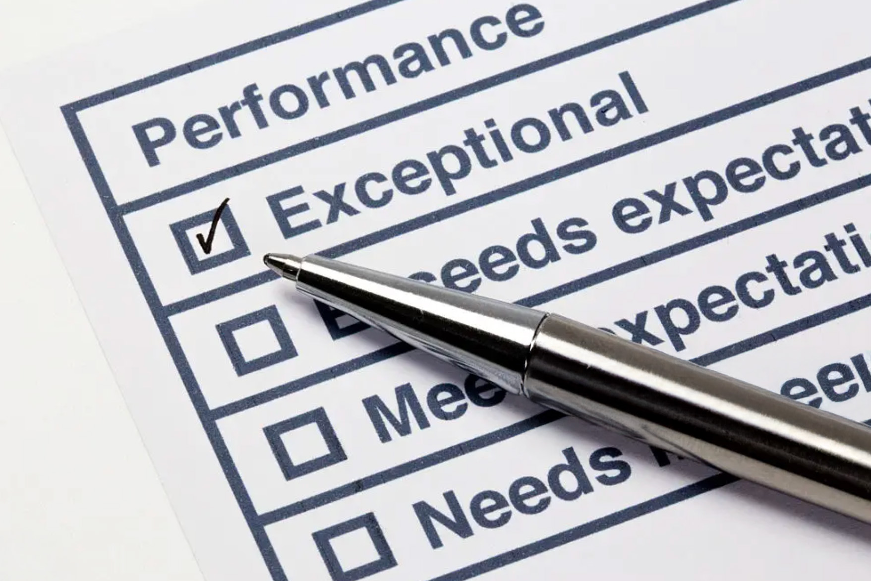 Close-up of a performance evaluation form with “Exceptional” checked and a pen resting across the page.