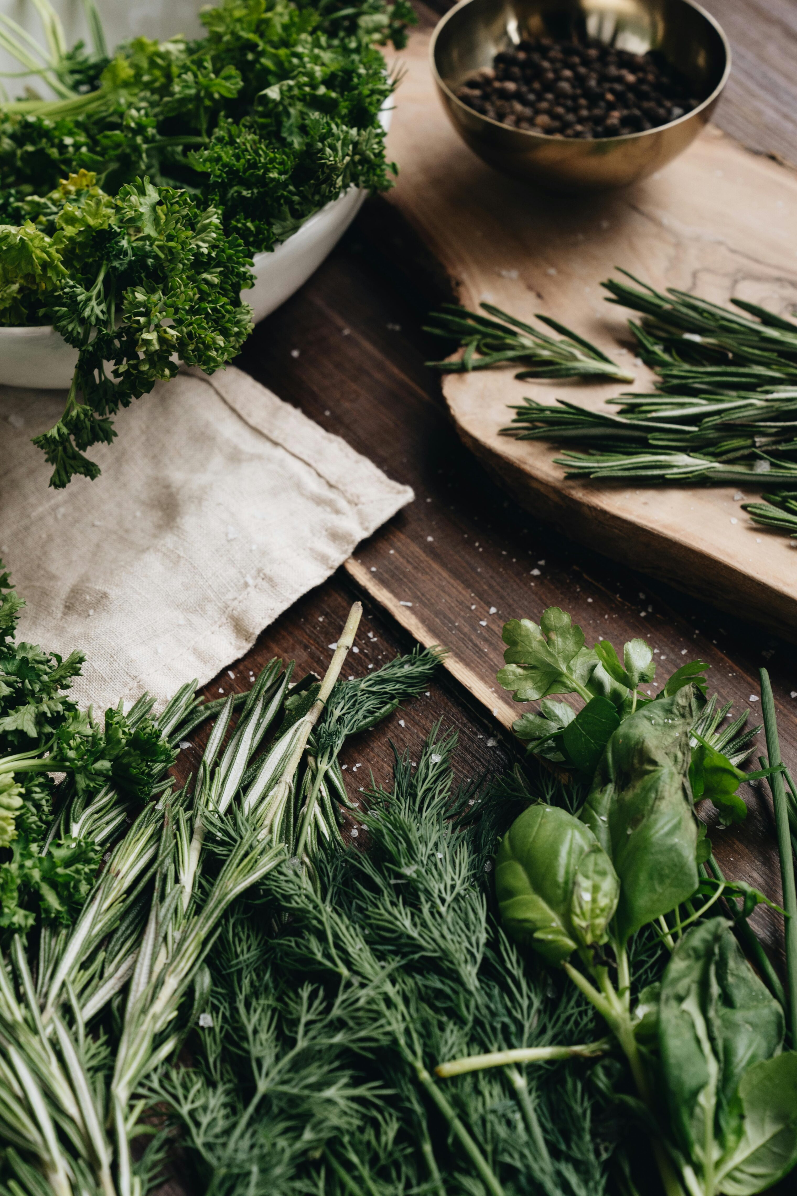 Various herbs laid out on a wooden table for cooking purposes.