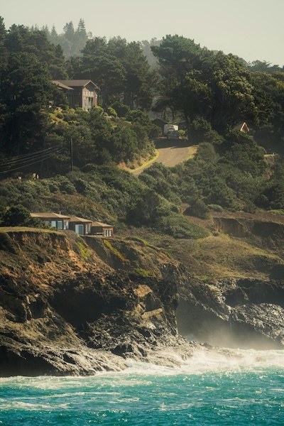 Seaside cliffs with wooded buildings in the distance.