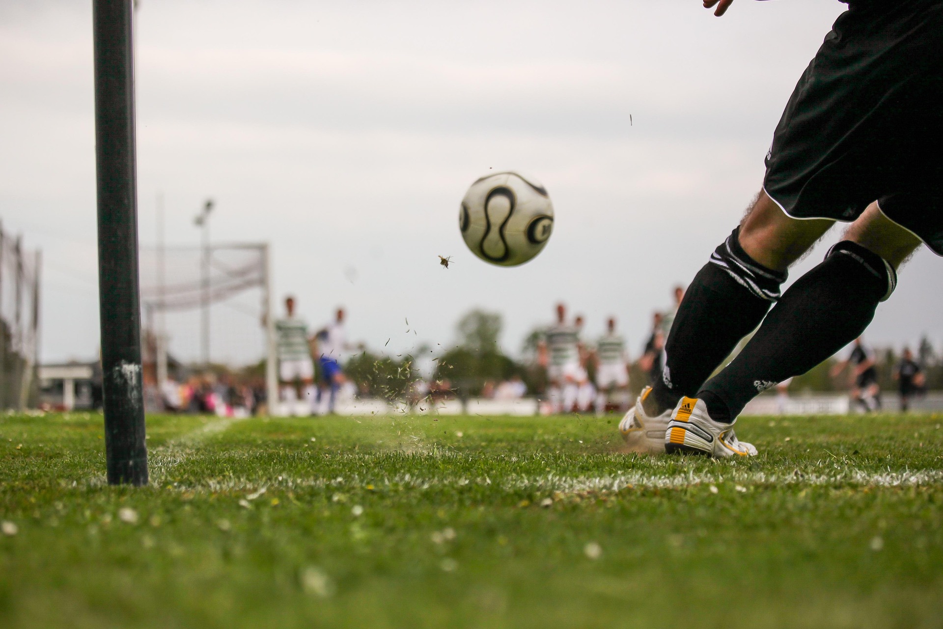 Person in cleats kicking soccer ball on turf
