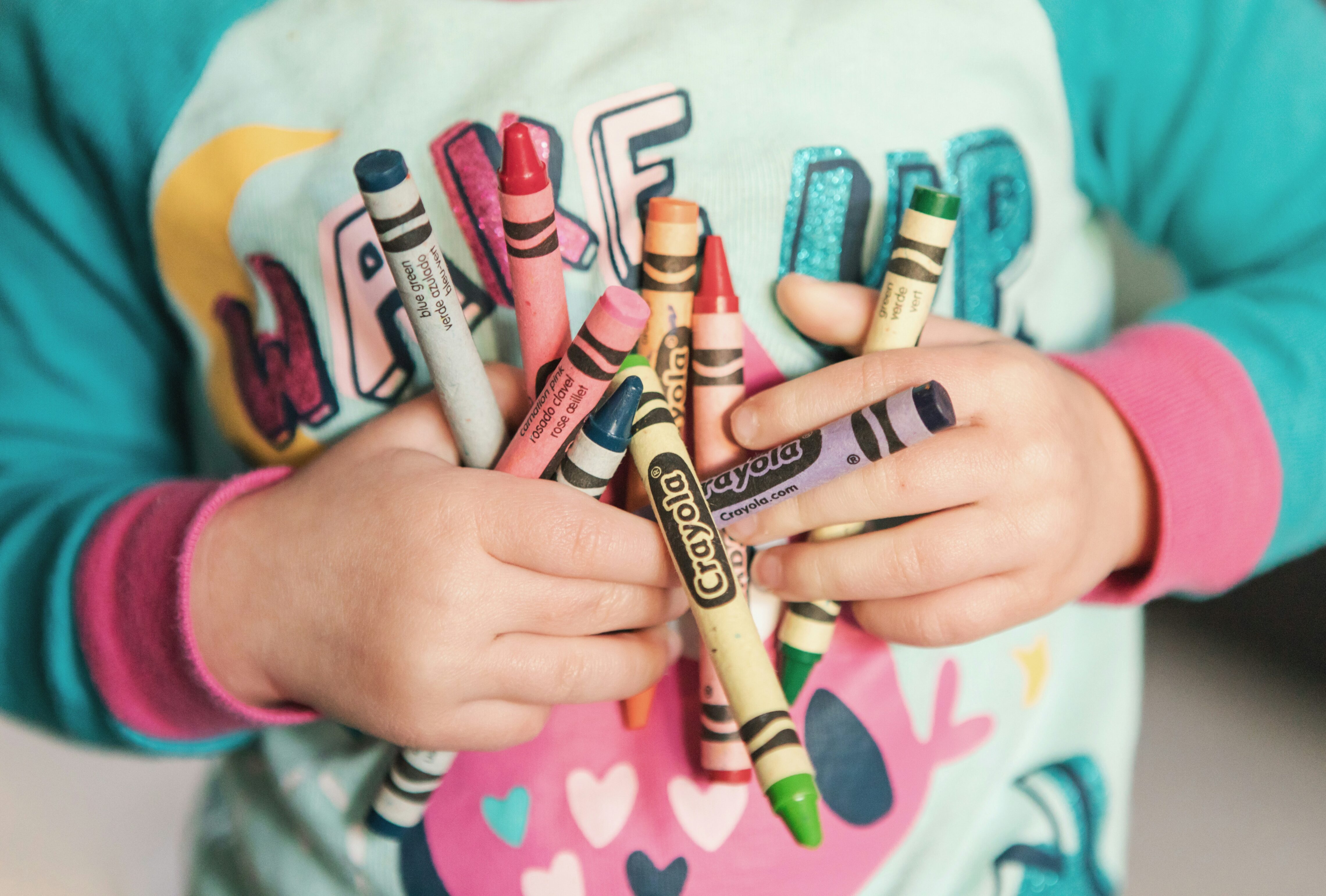 Close-cropped shot of a toddler holding crayons