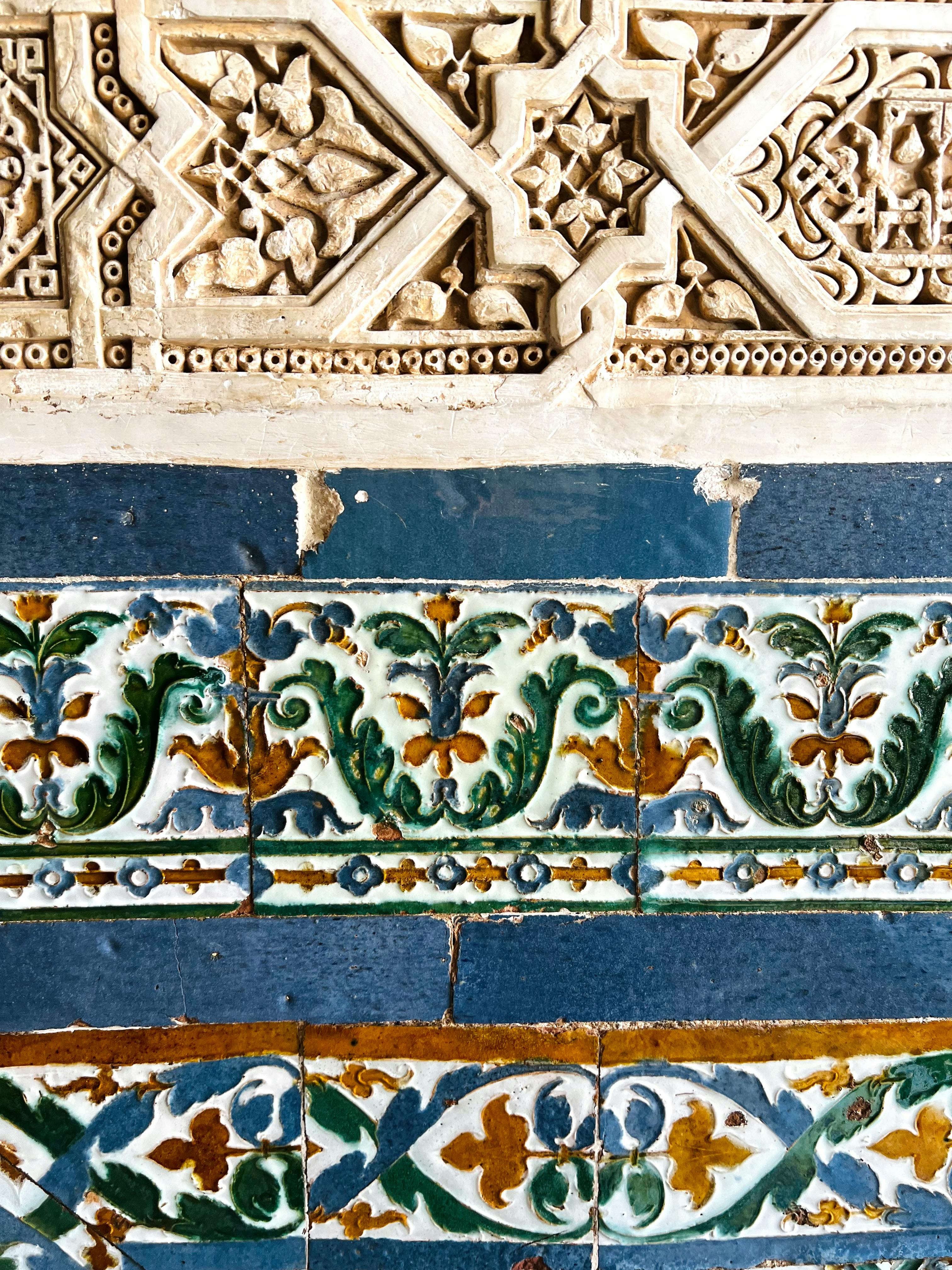 Close-up shot of colorful floral tile with a strip of light tan-colored intricate stonework at the top
