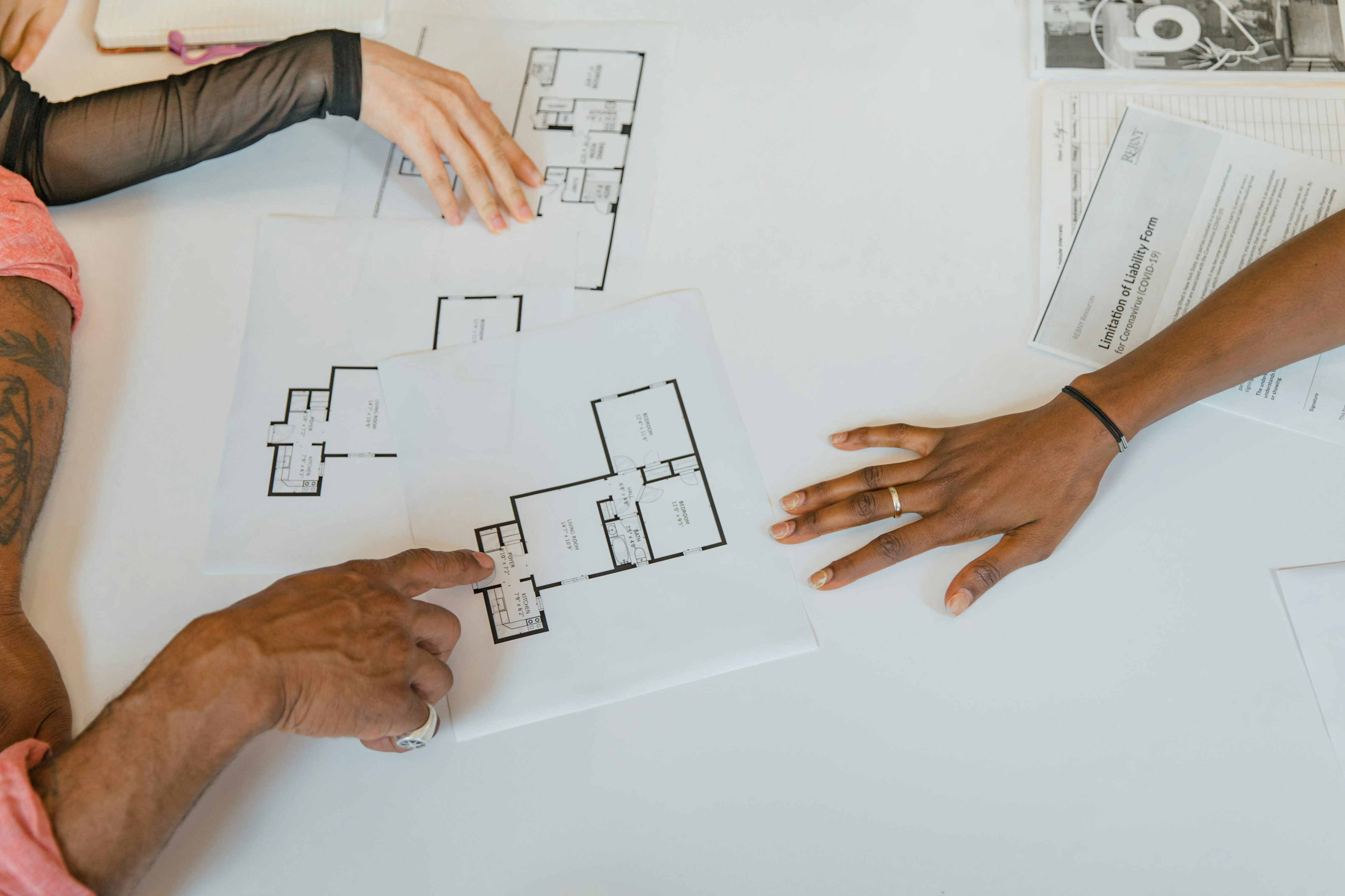 Multiple people's hands working with printed floor plans