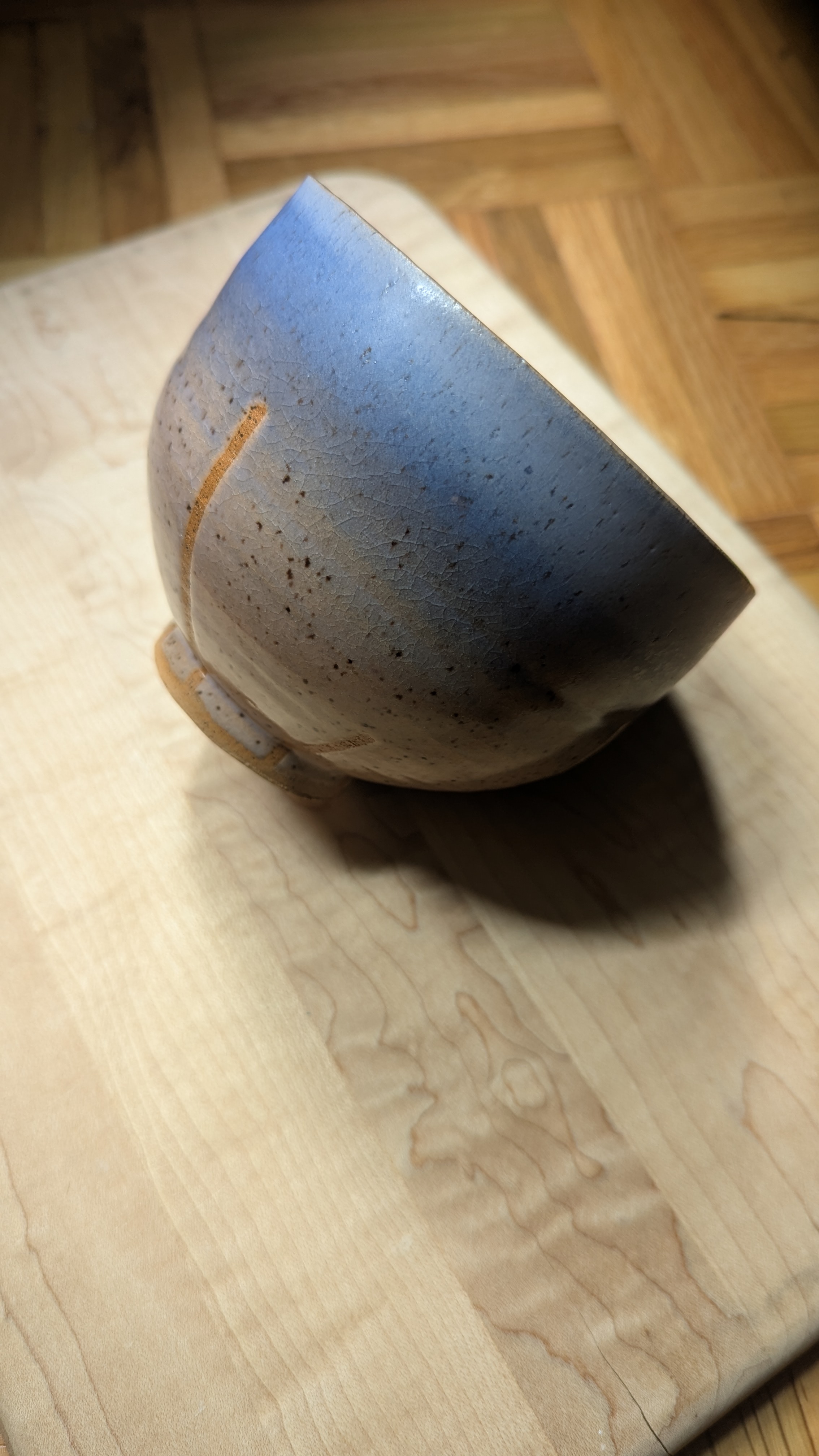 Small ceramic bowl on its side glazed with blue and earthy tones