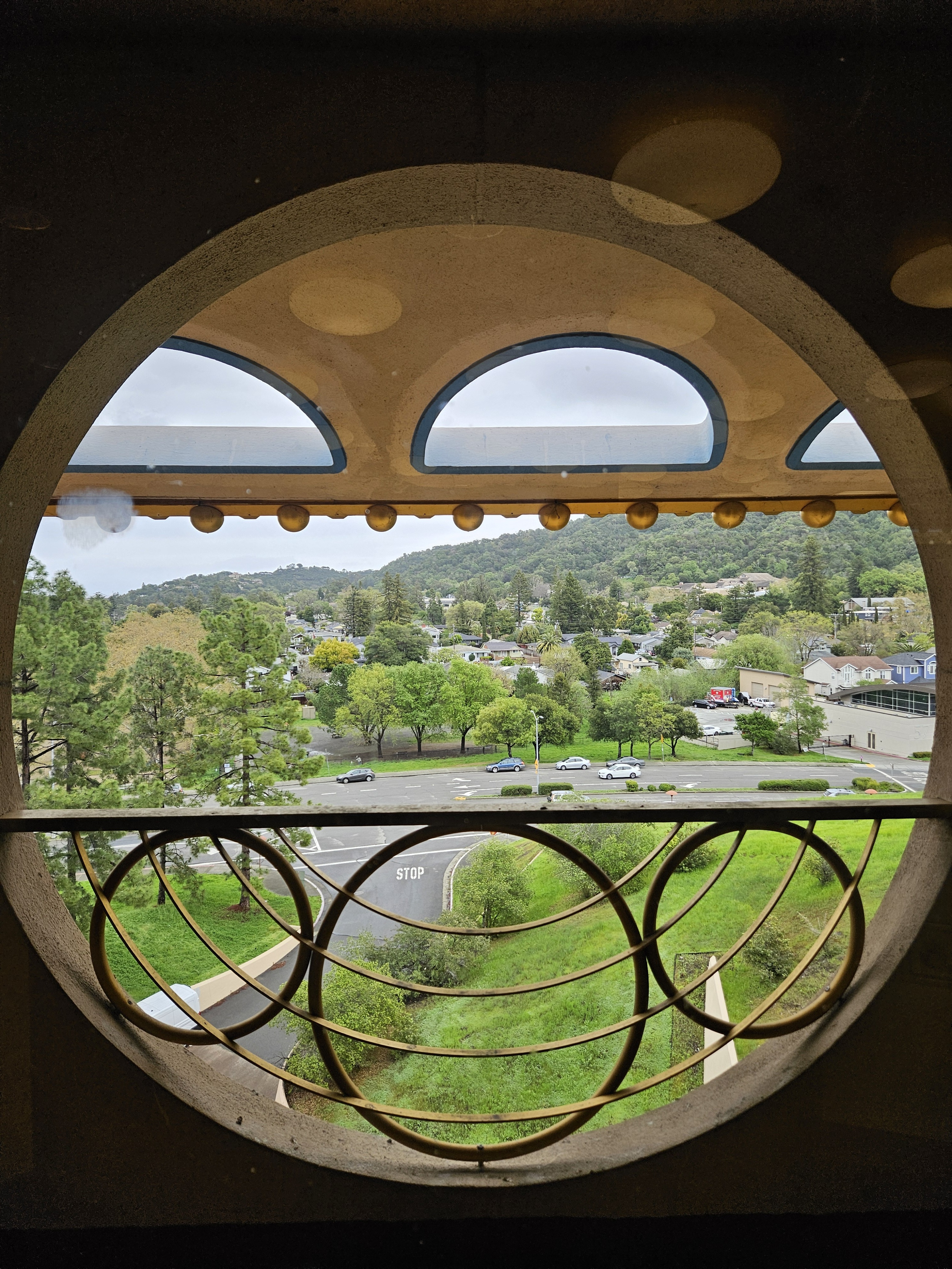 A view of a green landscape through the iconic circular windows of the Marin Civic Center