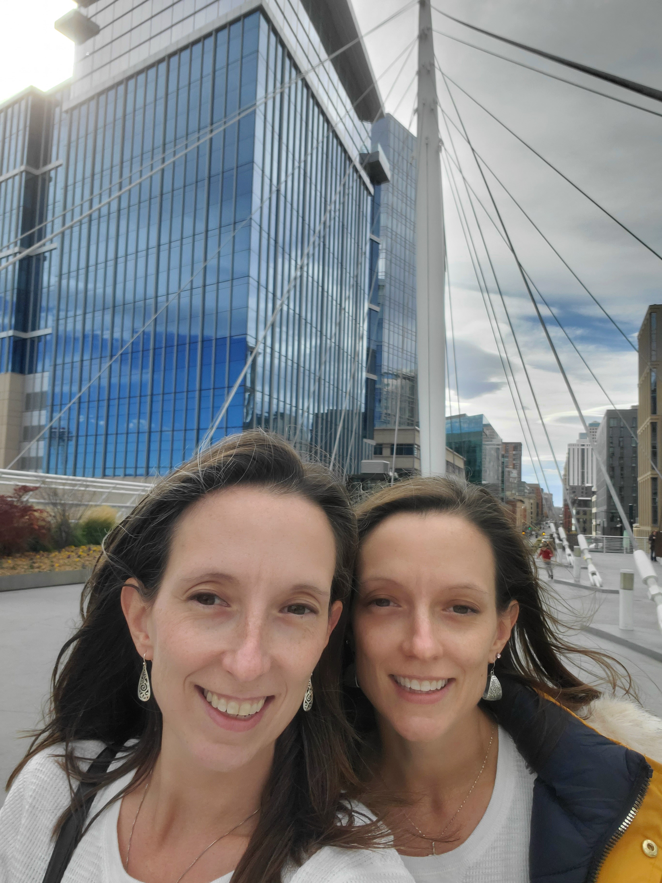 Architect Lindsey Moder and her twin sister in front of large, reflective buildings