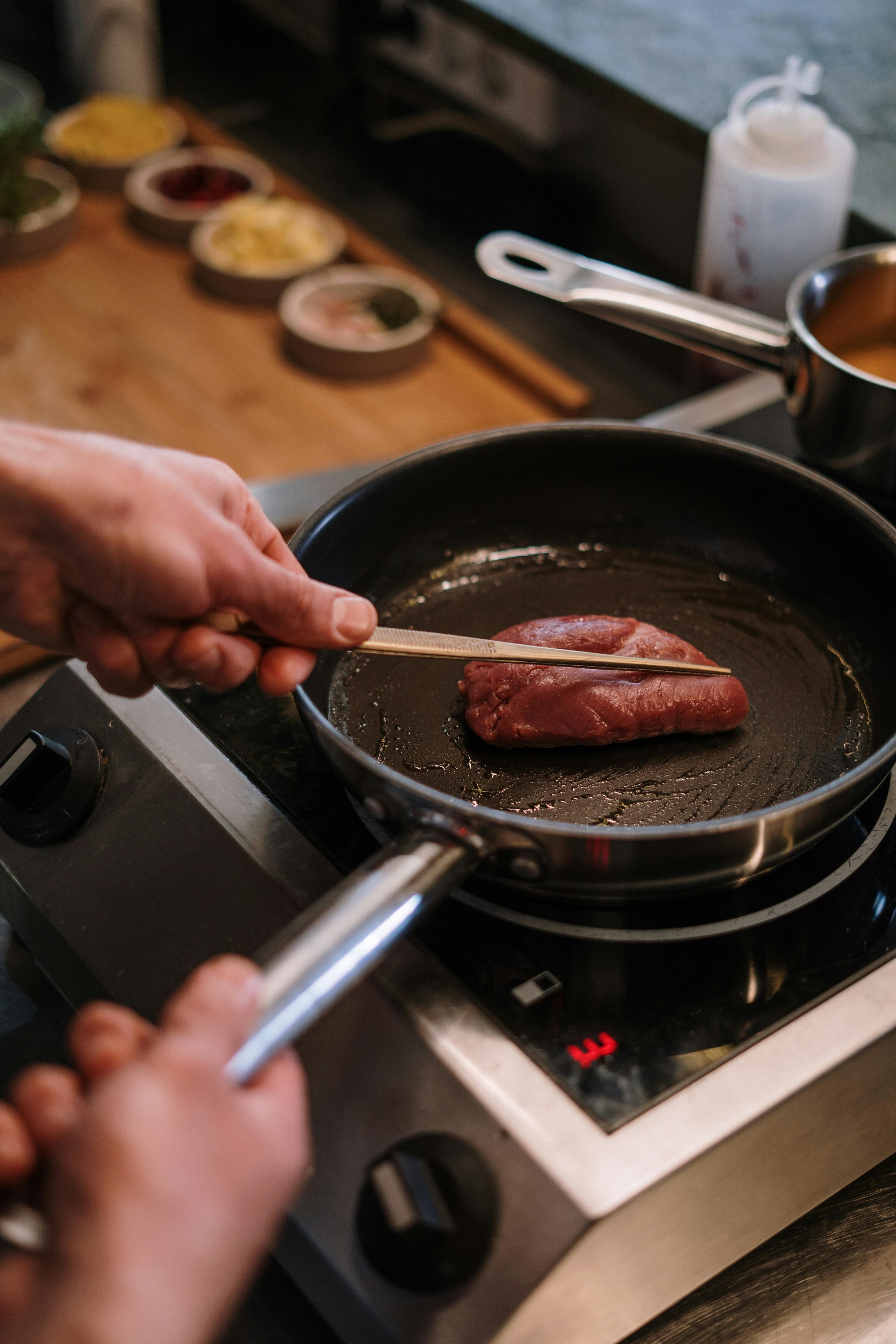 Person cooking a piece of meat on a frying pan