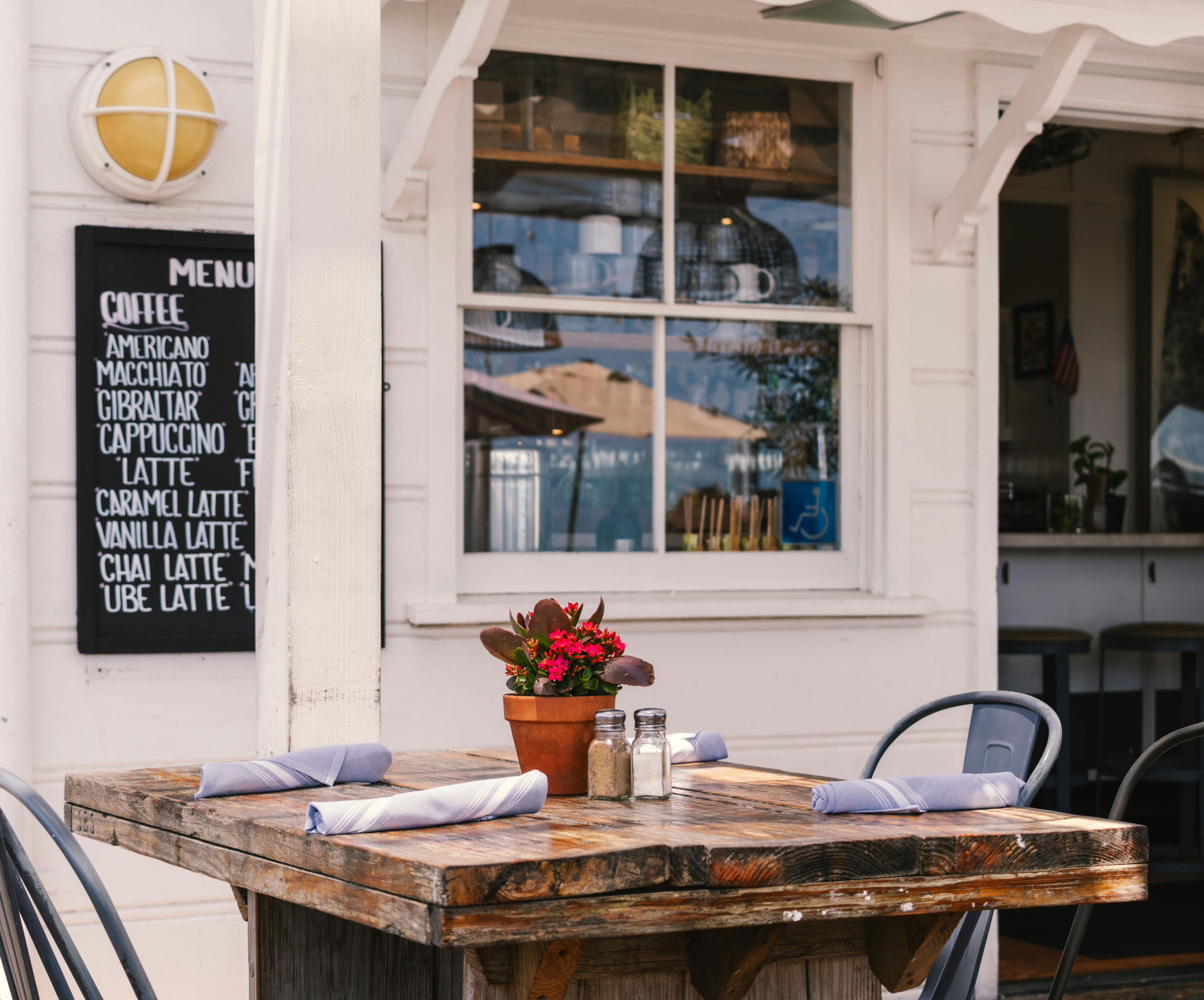 Outdoor cafe with table setting in front of a white clapboard facade