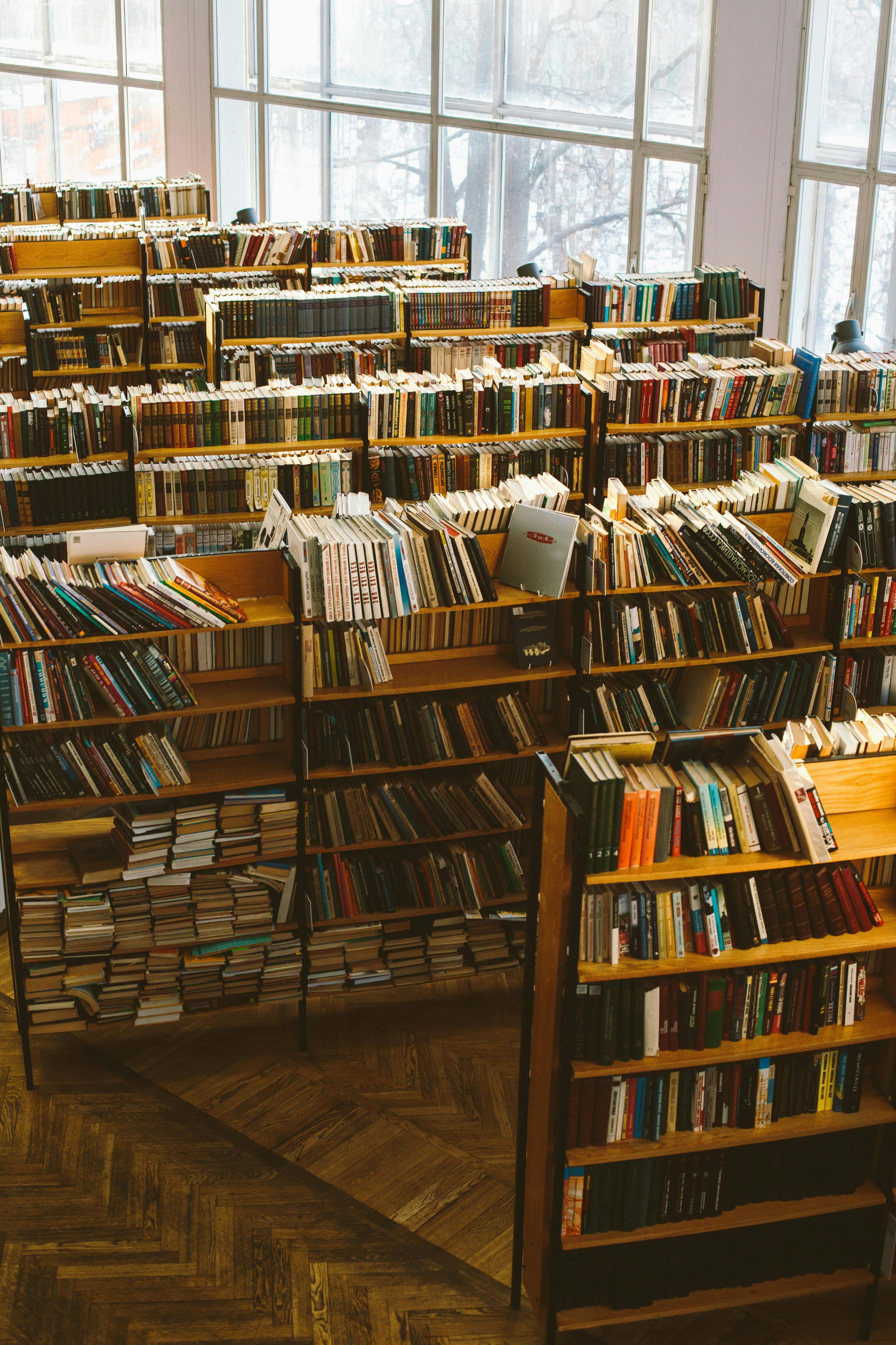 An overflowing collection of books in rows of wooden bookshelves