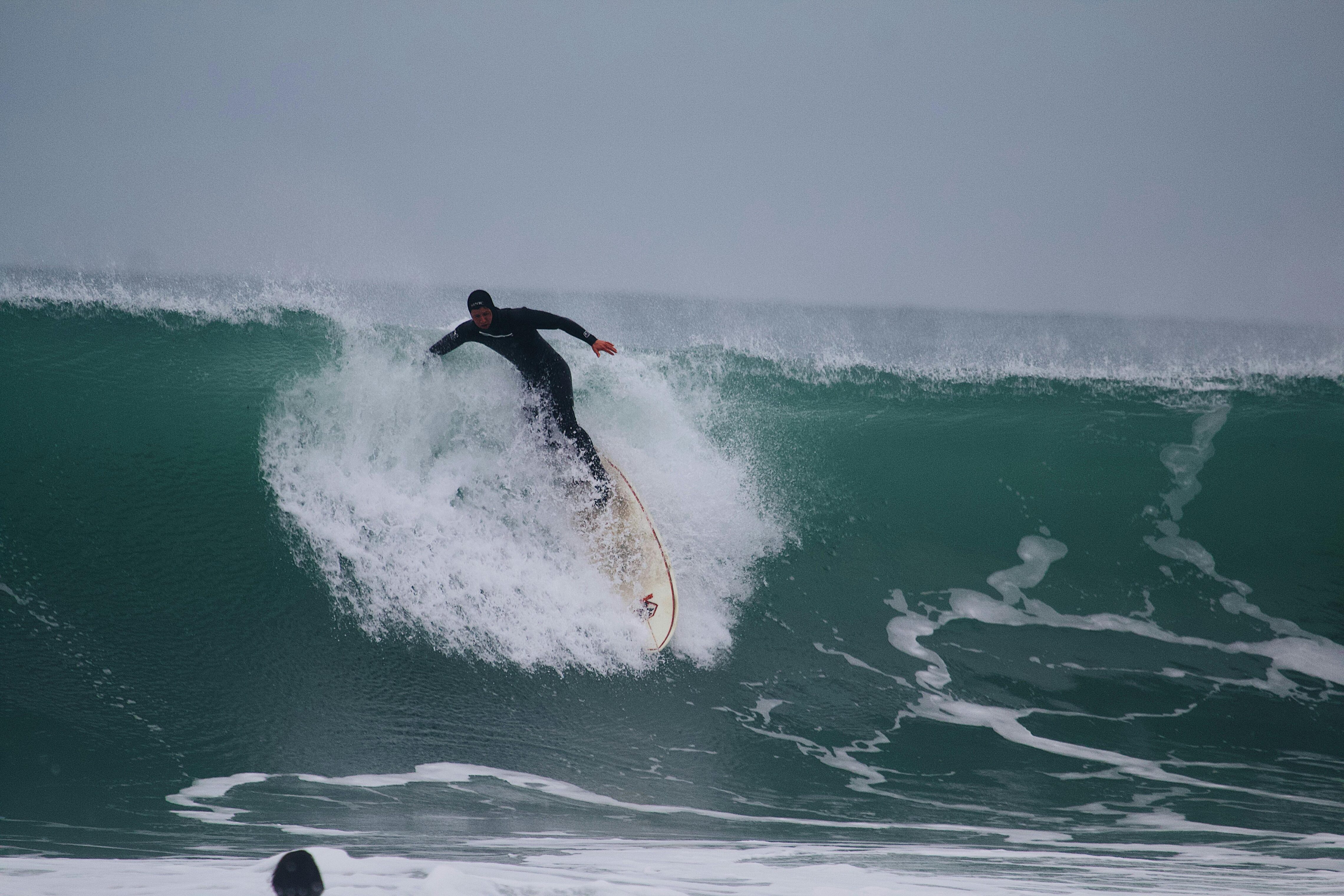 A person surfing a large wave on a cloudy day