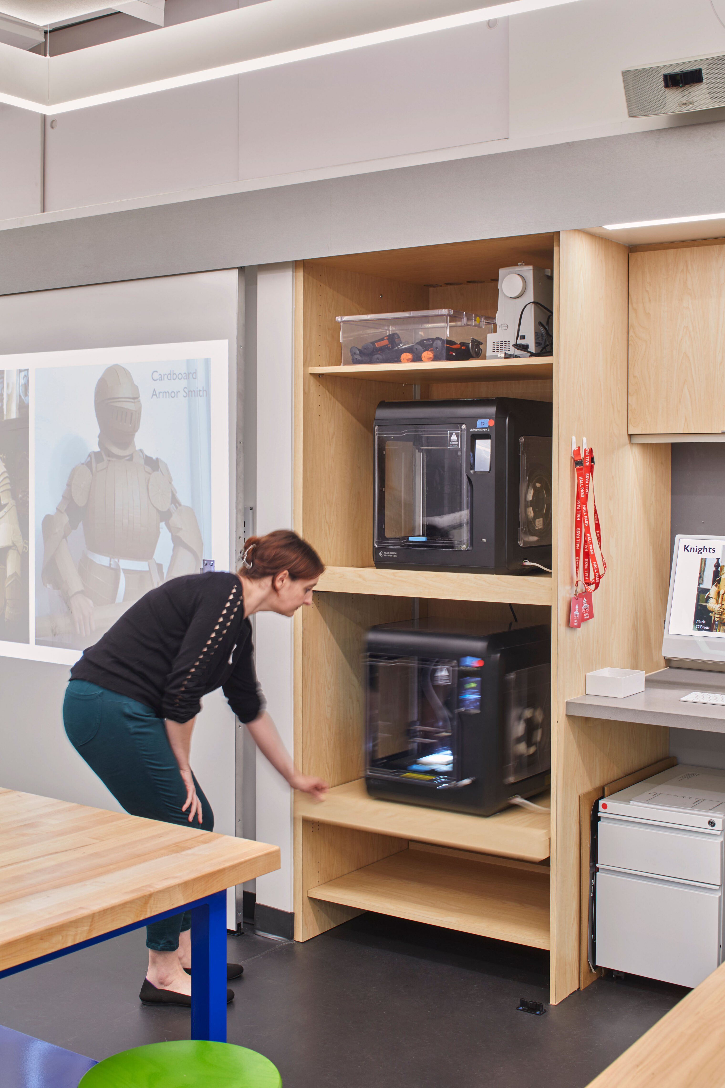A teacher uses a 3D printer integrated into built-in shelving within the Engineering Studio’s fabrication area.