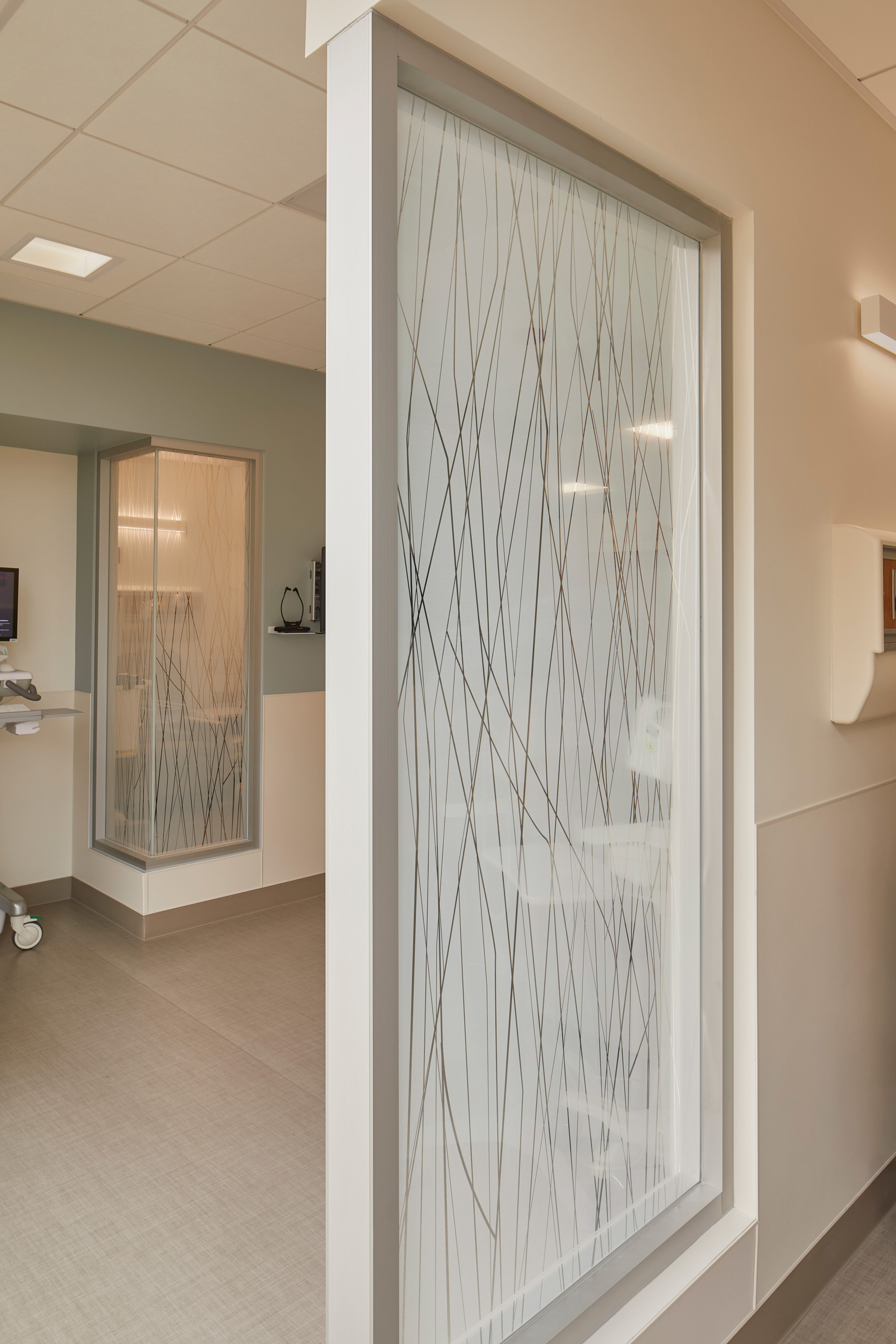 Close-up view of patterned privacy glass panels separating infusion treatment rooms from the clinic corridor.