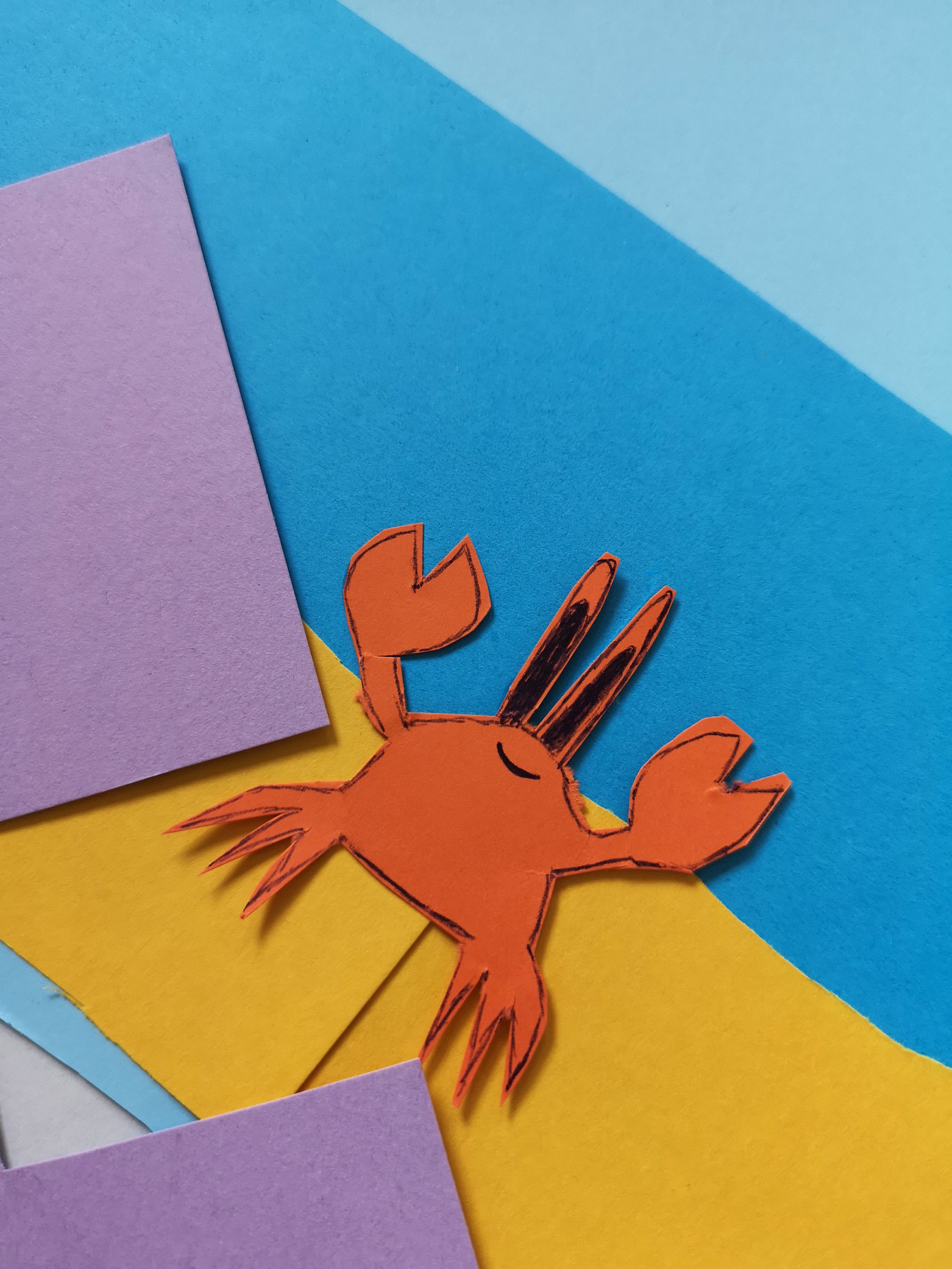 A small paper crab cutout on other colorful paper.
