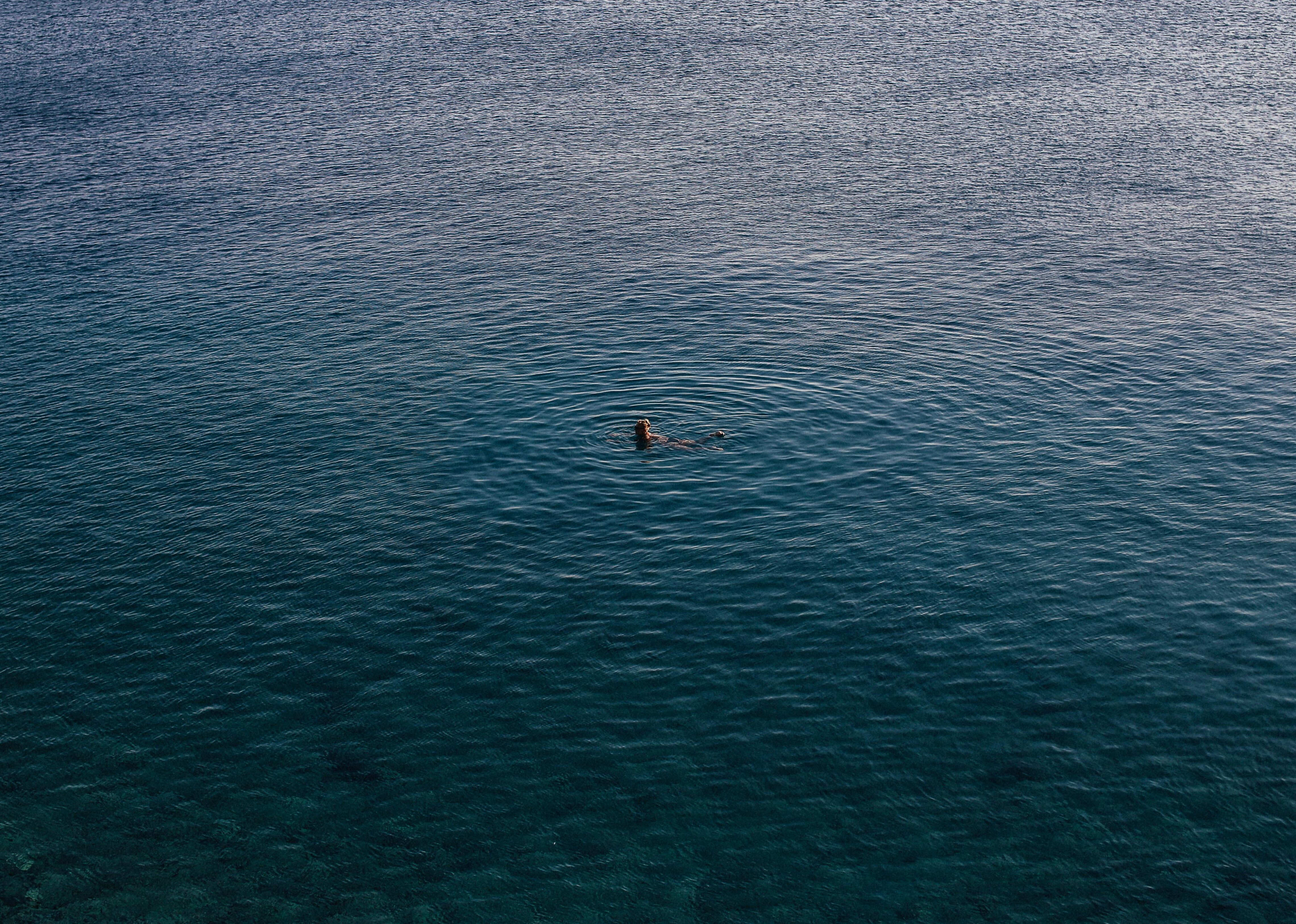 A person in a large body of water from very far away.