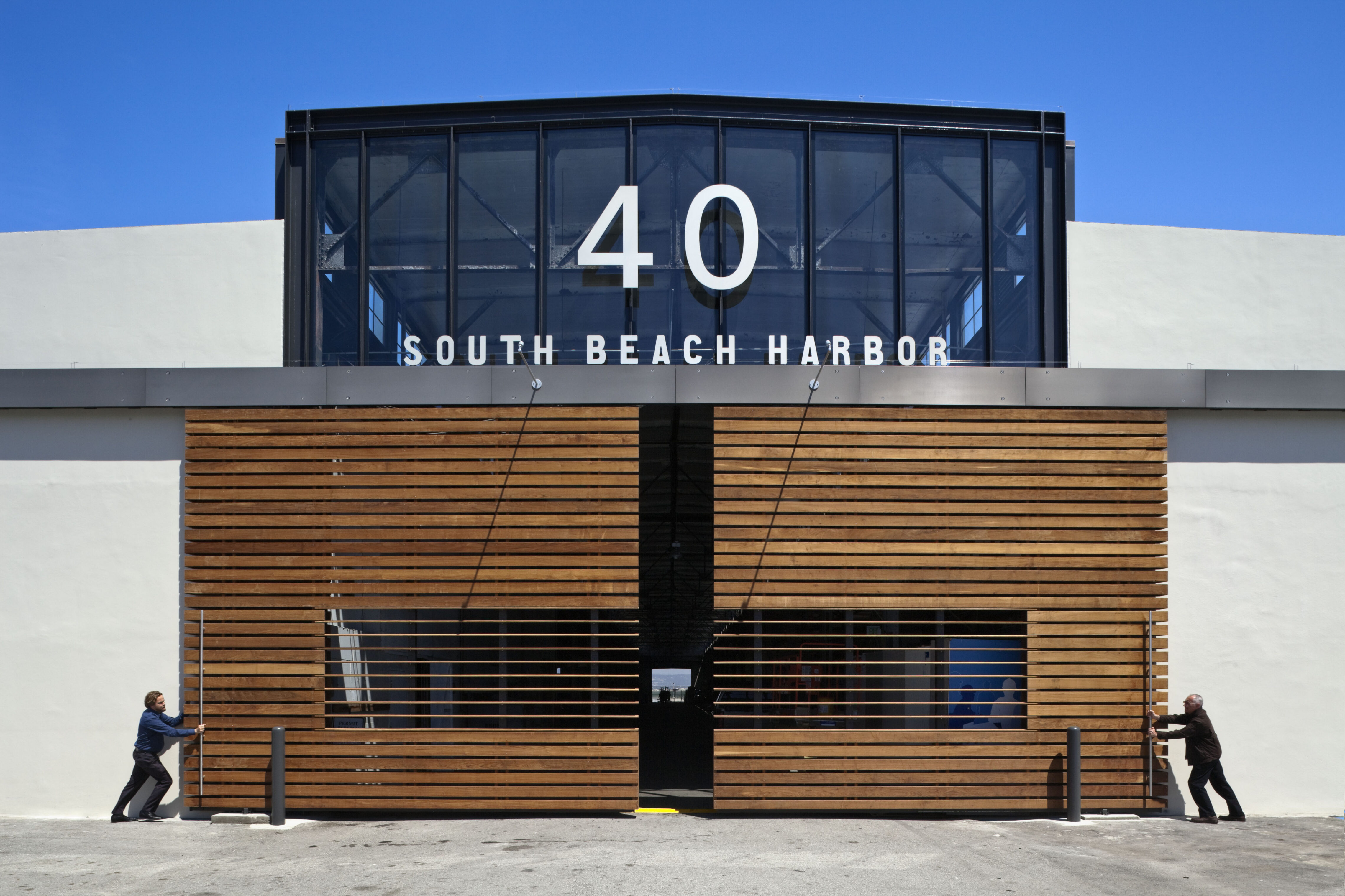 Front elevation of South Beach Harbor’s Building 40 with the large wood-slat doors partially opened to reveal the interior.